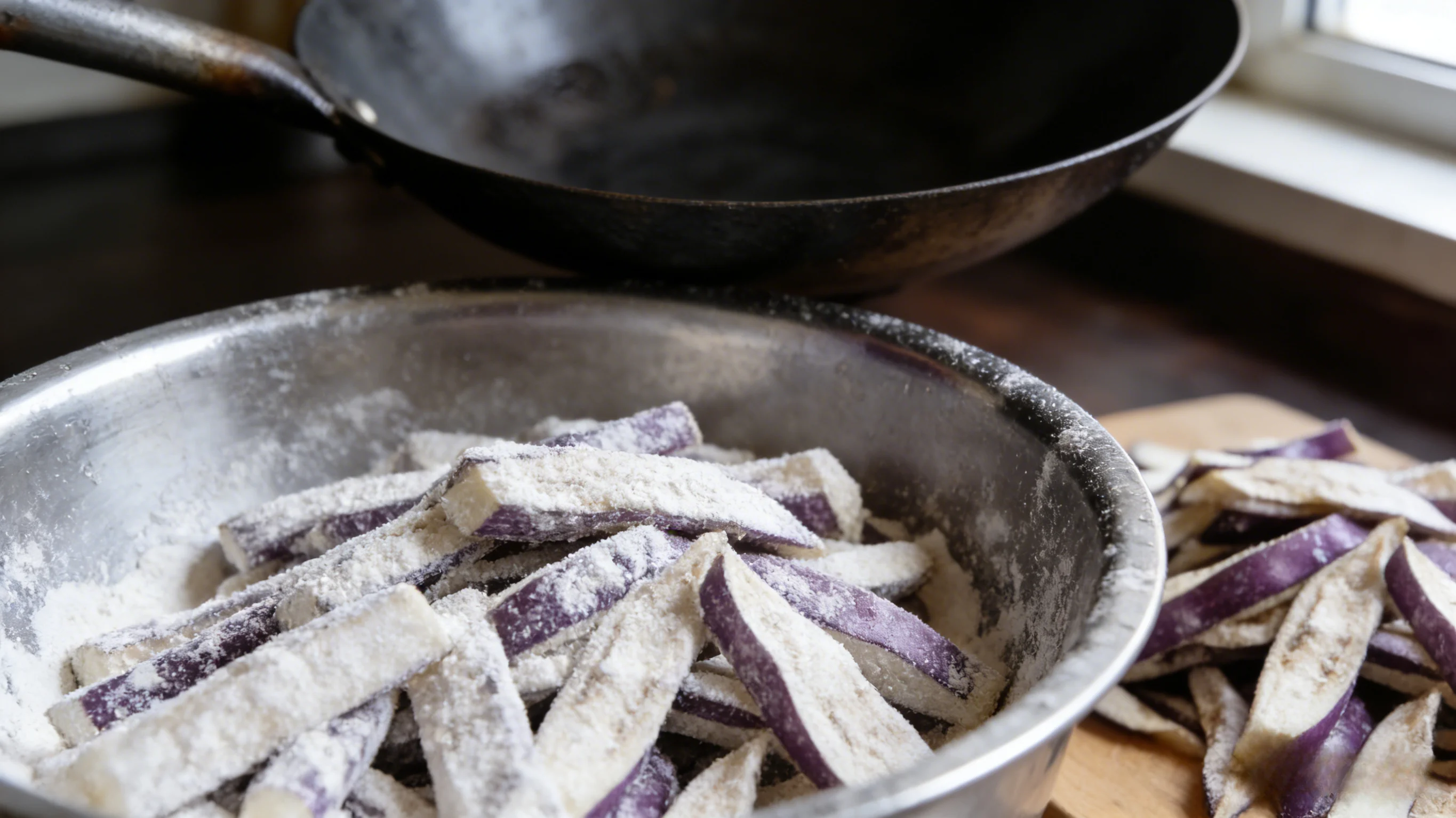Coating eggplant strips evenly with white cornstarch